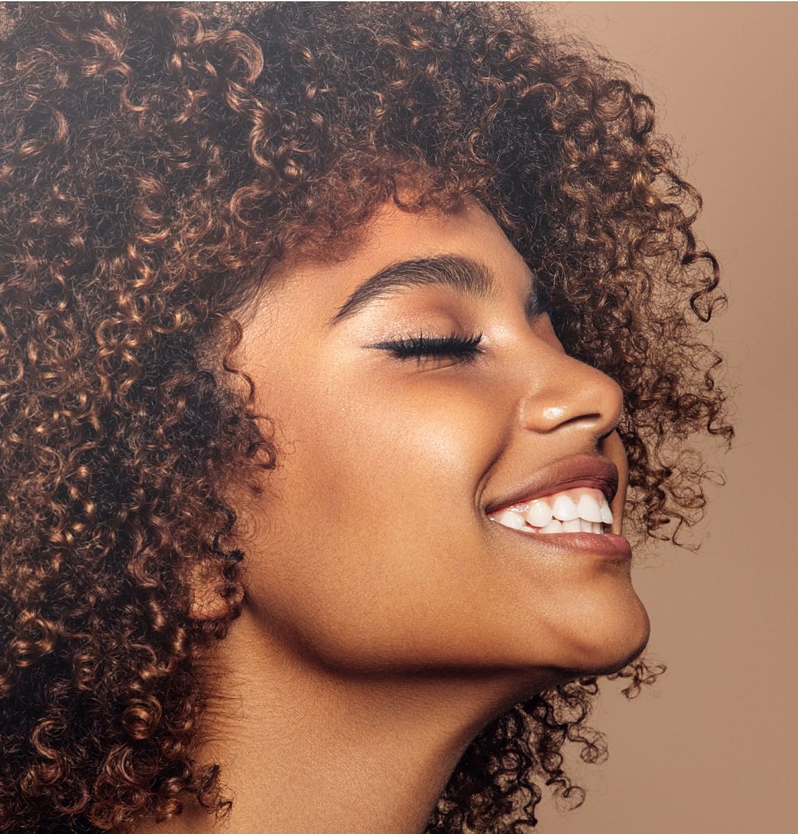Woman with curly hair smiling gracefully.