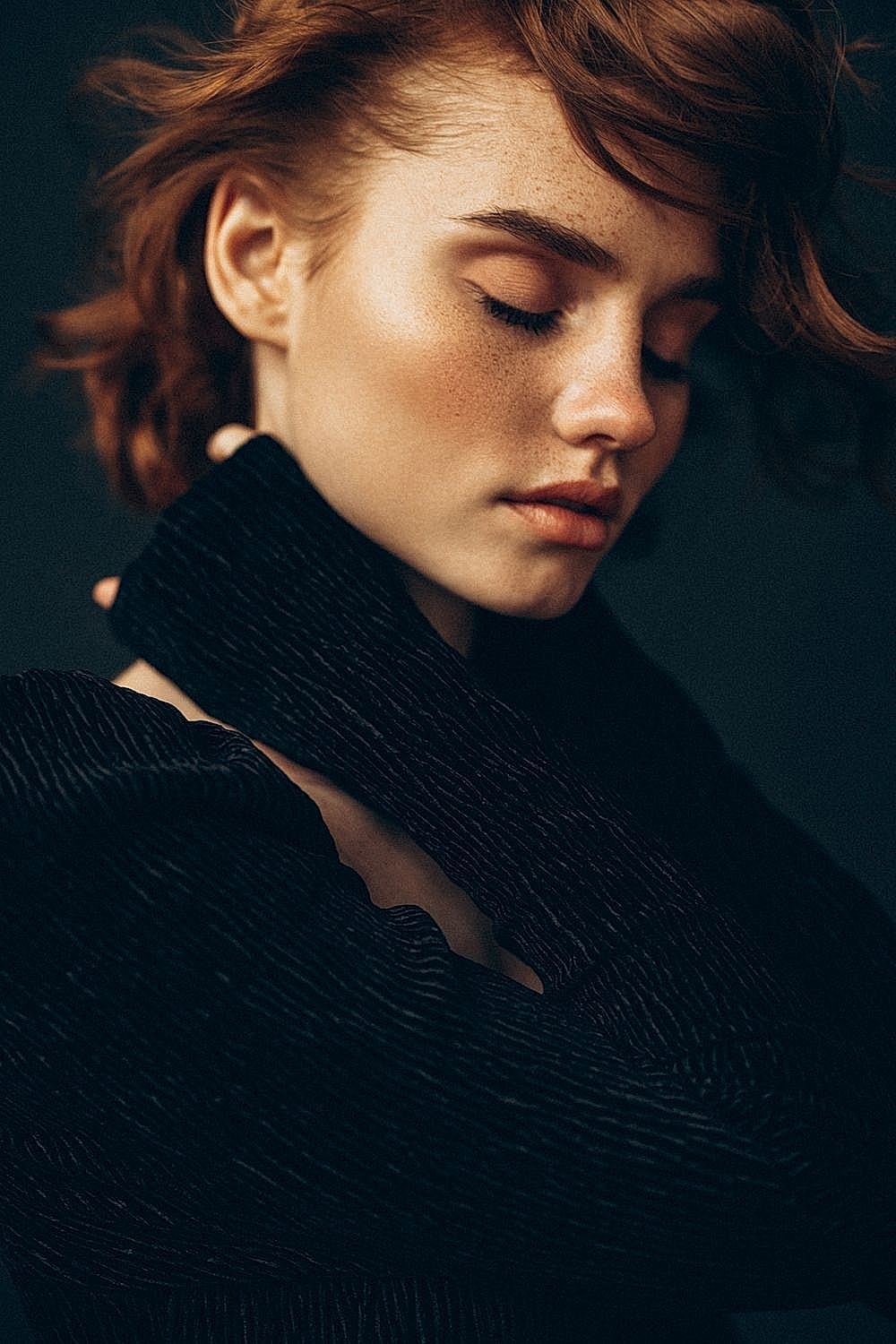 Pensive woman with curly hair and freckled skin.