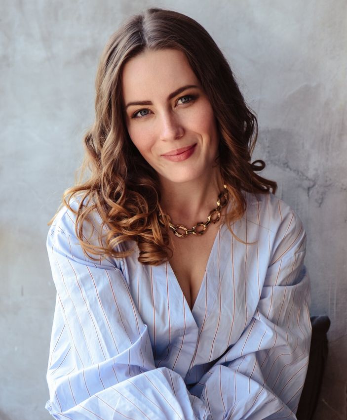 Woman smiling in stylish blouse and necklace.