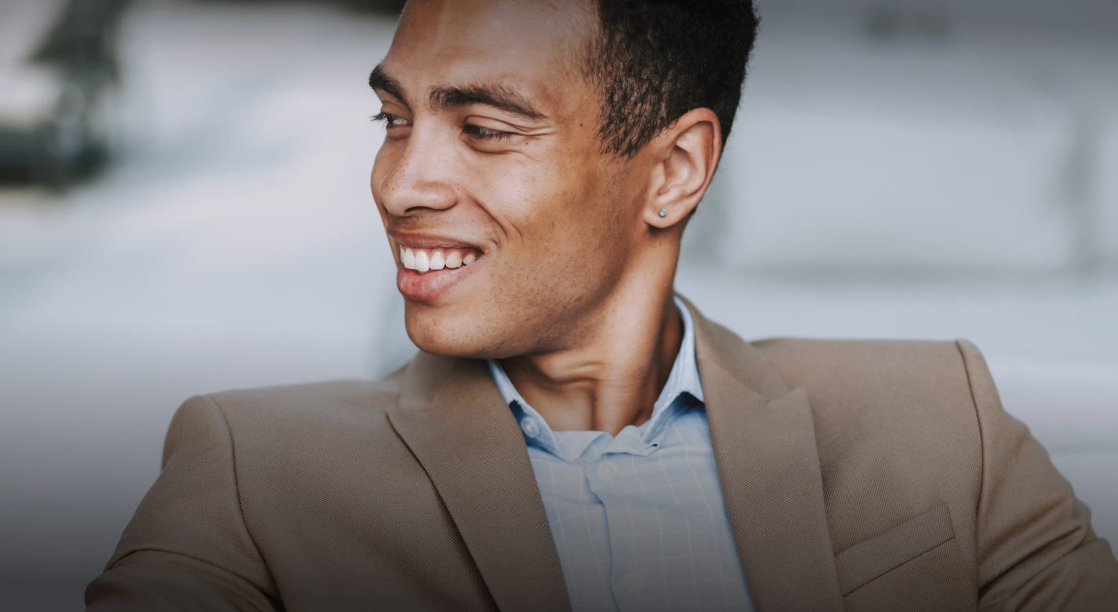 Smiling man in a beige suit jacket.