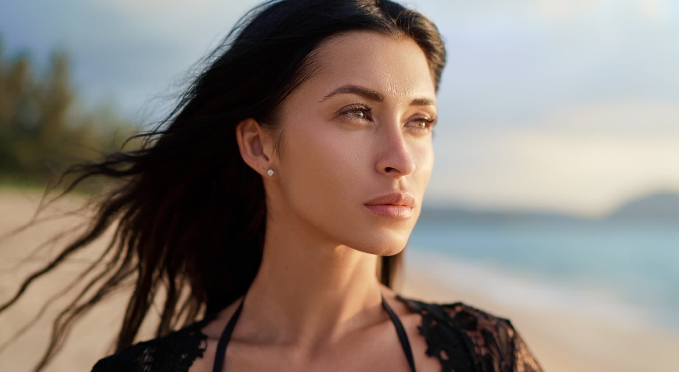 Woman gazing at the sea with flowing hair.